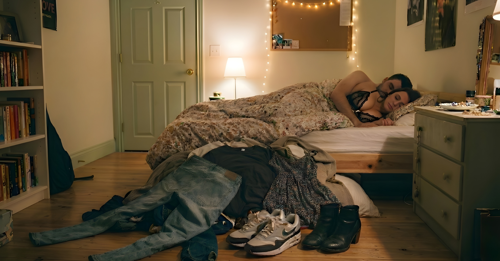man and woman in bed with shoes and clothes on the floor.